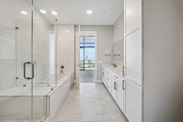 a bathroom with a double vanity sink a large mirror and a glass door shower
