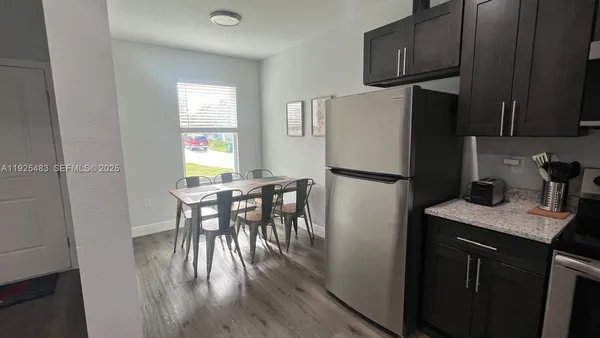 a kitchen with a table chairs refrigerator and microwave