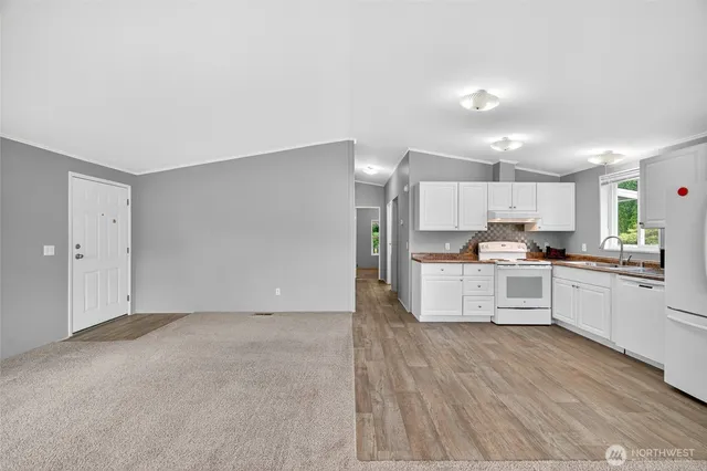 a large white kitchen with stainless steel appliances cabinets a sink and a stove