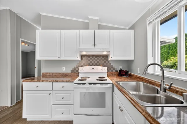 a kitchen with granite countertop a sink stove and cabinets