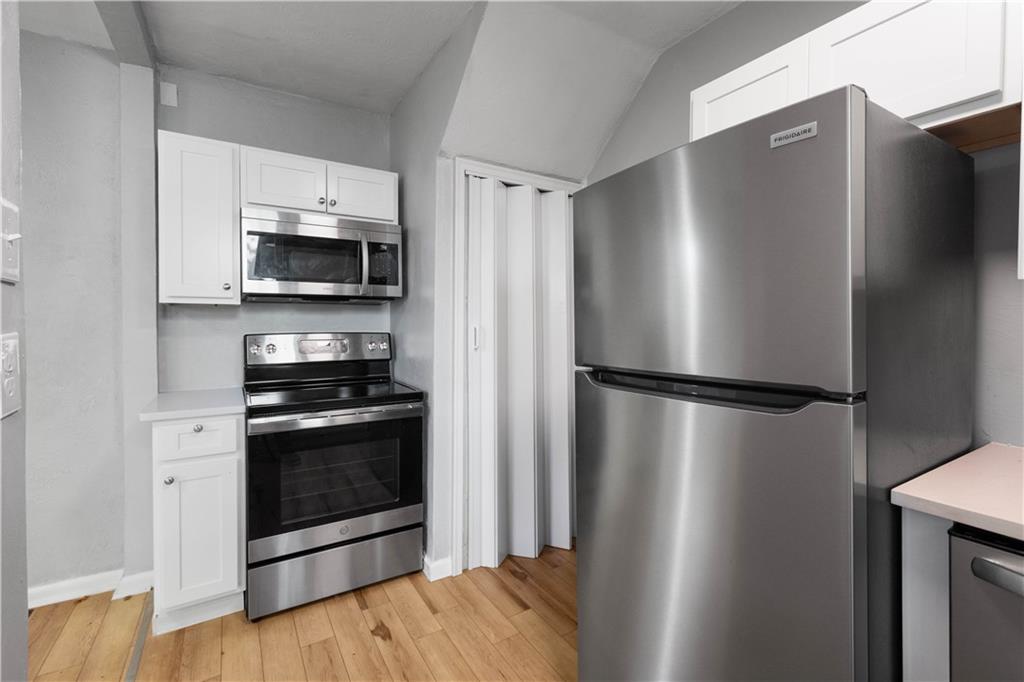 243 Castle Shannon Boulevard, Unit 243 Pittsburgh, PA 15228 - Photo 12 of 26 a kitchen with stainless steel appliances a refrigerator a stove top oven and wooden floor