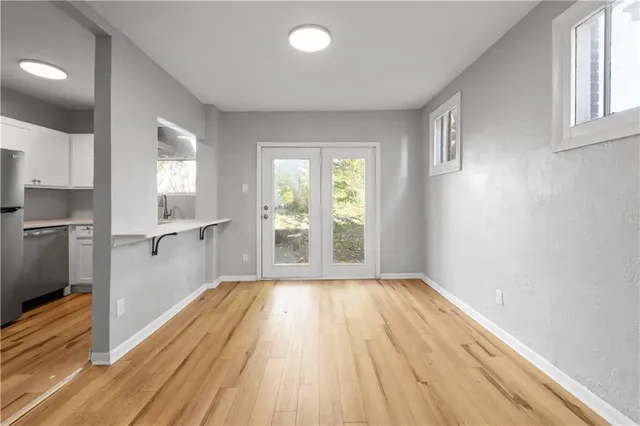 a view of a room with wooden floor electronic appliances and windows