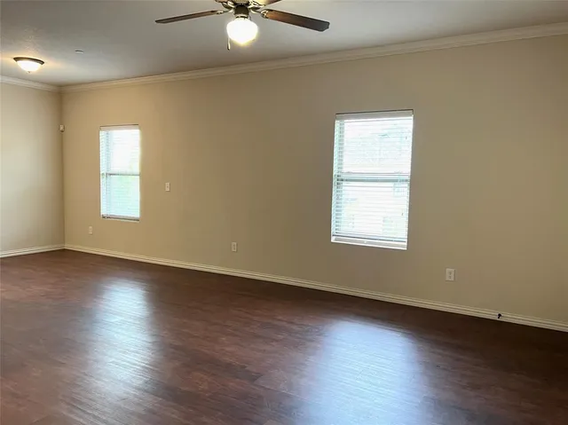 an empty room with wooden floor fan and windows