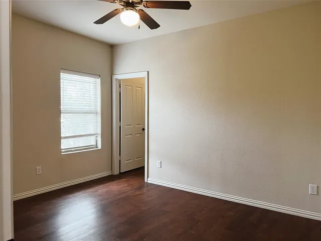 an empty room with wooden floor fan and windows