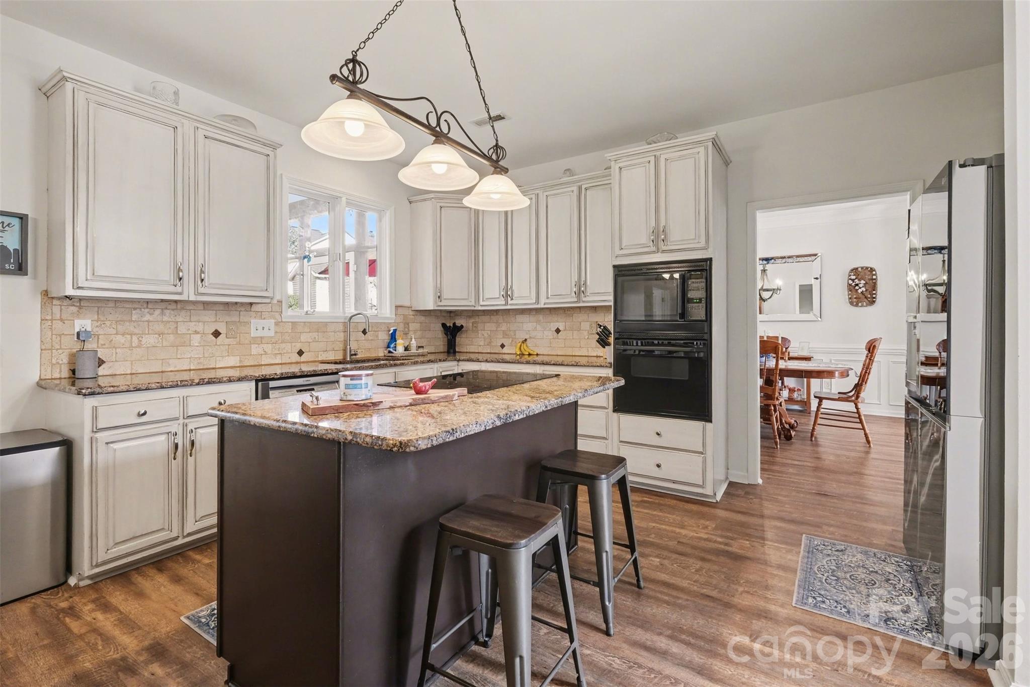 523 Whitehead Court Fort Mill, SC 29708 - Photo 14 of 48 a kitchen with stainless steel appliances granite countertop a stove top oven a refrigerator a sink a dining table and chairs with wooden floor