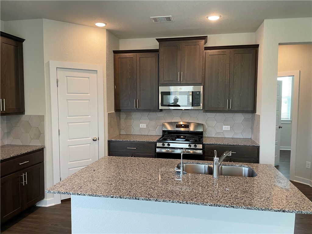 609 Paddock Lane Georgetown, TX 78626 - Photo 21 of 40 Gleaming granite countertops pair beautifully with dark wood cabinetry and modern stainless steel appliances.