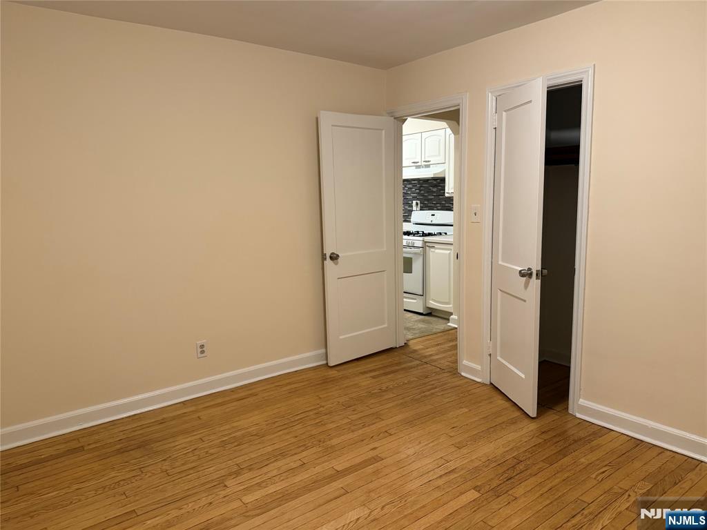 40 Hope Street, Unit 1 East Rutherford, NJ 07073 - Photo 11 of 14 an empty room with wooden floor and a kitchen