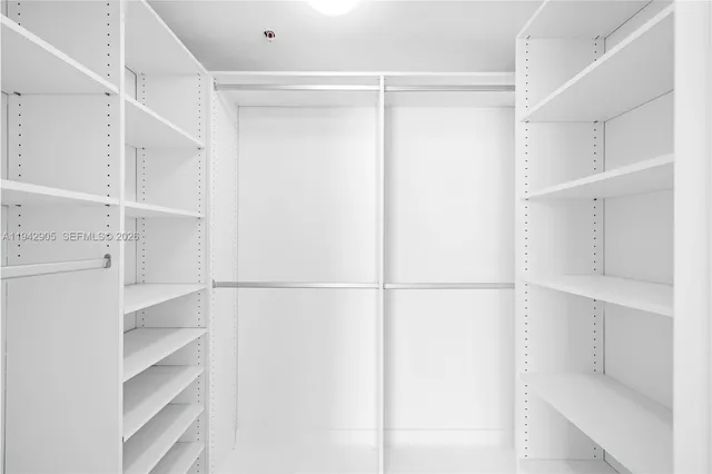 a view of walk in closet with clothes and shoes