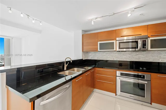 a kitchen with stainless steel appliances granite countertop a sink stove and microwave