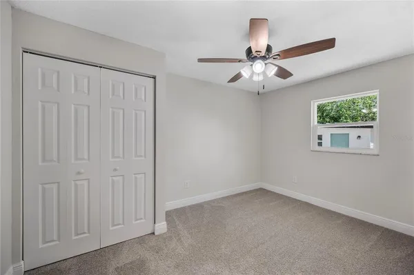 an empty room with windows and fan
