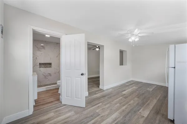 an empty room with wooden floor and a ceiling fan