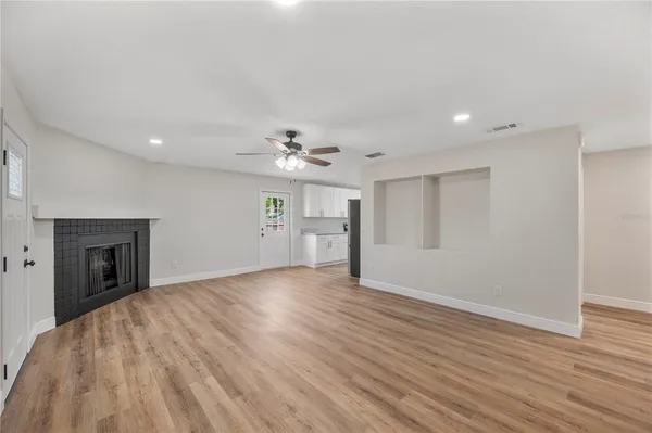 a view of an empty room with wooden floor and a fireplace