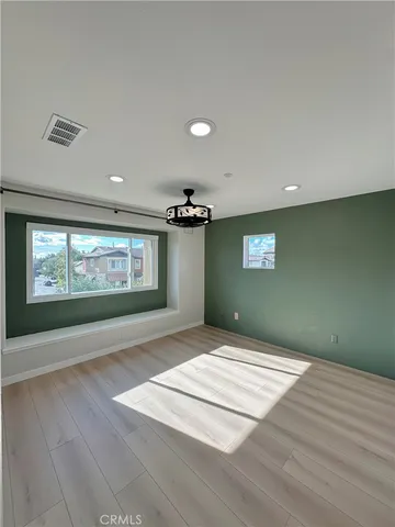 a view of an empty room with a window and wooden floor