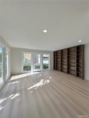 a view of an empty room with a window and a kitchen