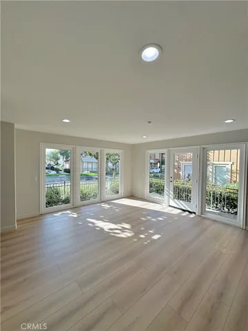 a view of an empty room with a large window and wooden floor
