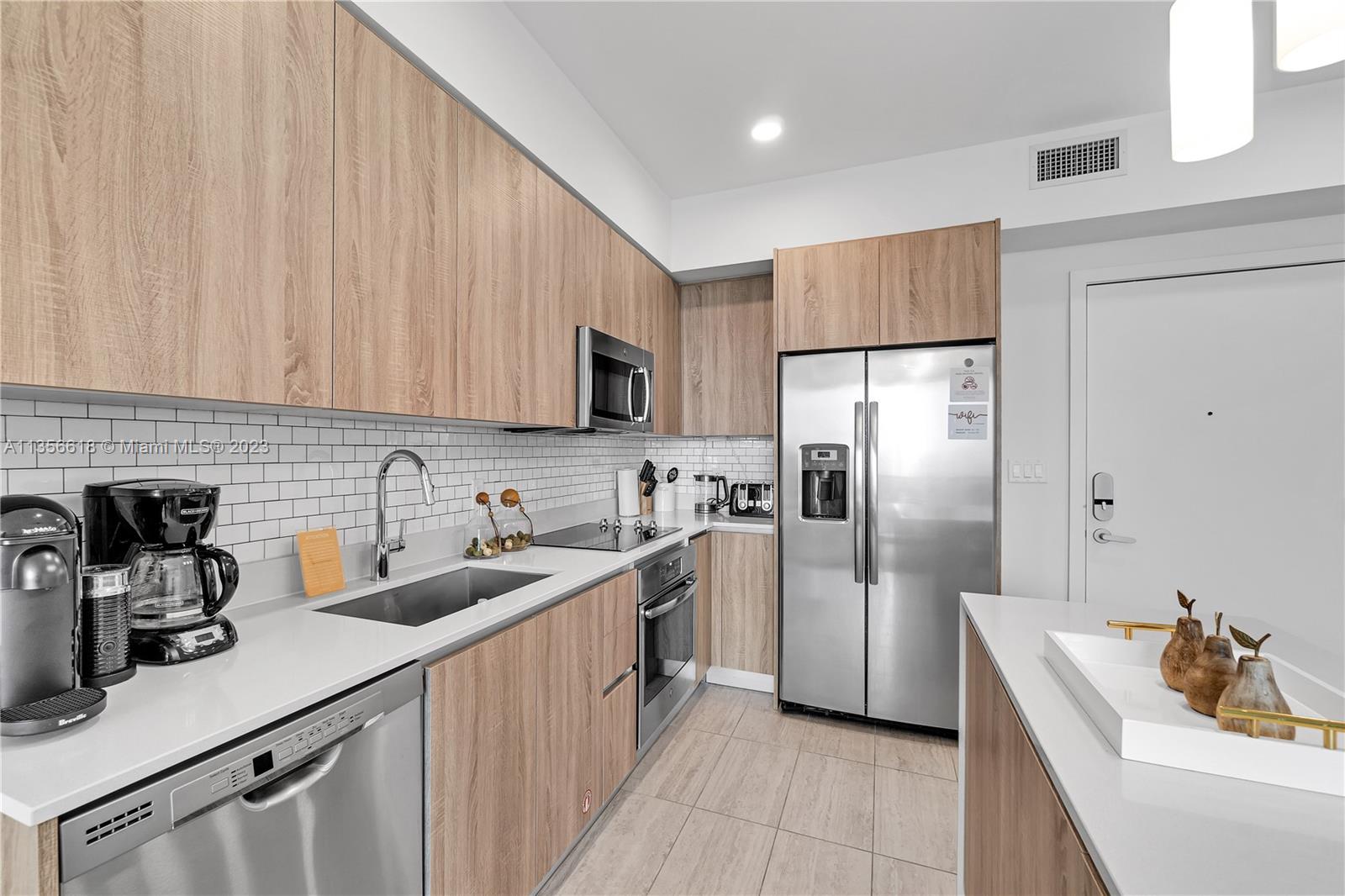 3900 Biscayne Boulevard, Unit S320 Miami, FL 33137 - Photo 6 of 42 a kitchen with a sink dishwasher a refrigerator and cabinets