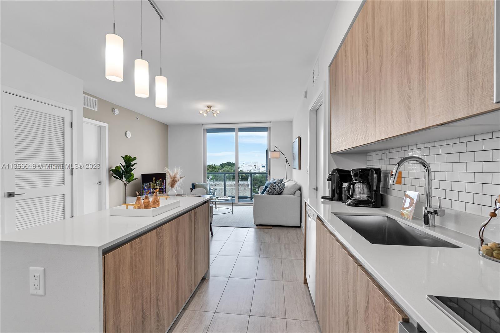 3900 Biscayne Boulevard, Unit S320 Miami, FL 33137 - Photo 9 of 42 a kitchen with stainless steel appliances a sink dishwasher a stove a kitchen island with chairs and wooden floor