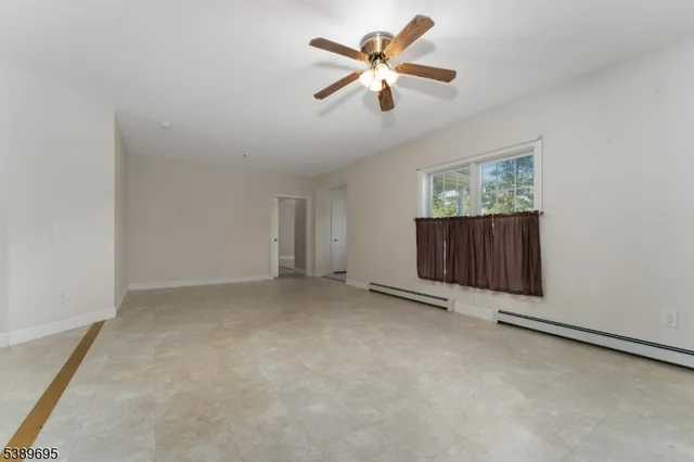 an empty room with windows and fan
