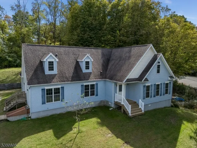 a view of a yard in front of a house with plants and large tree