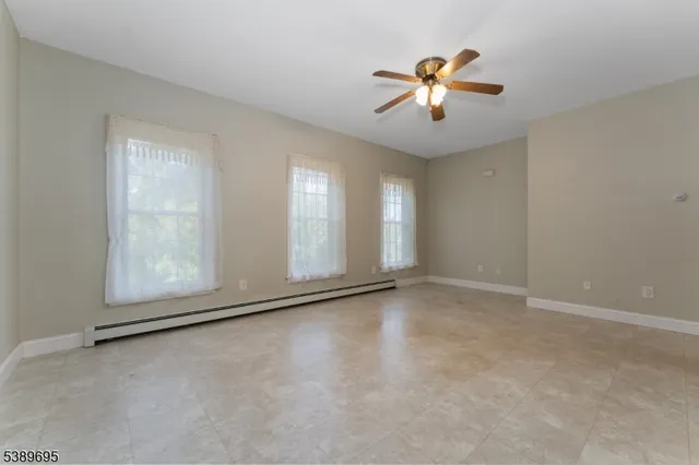 a view of an empty room with chandelier fan and fire place