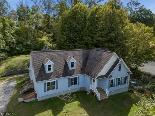 an aerial view of a house with yard and trees in the background