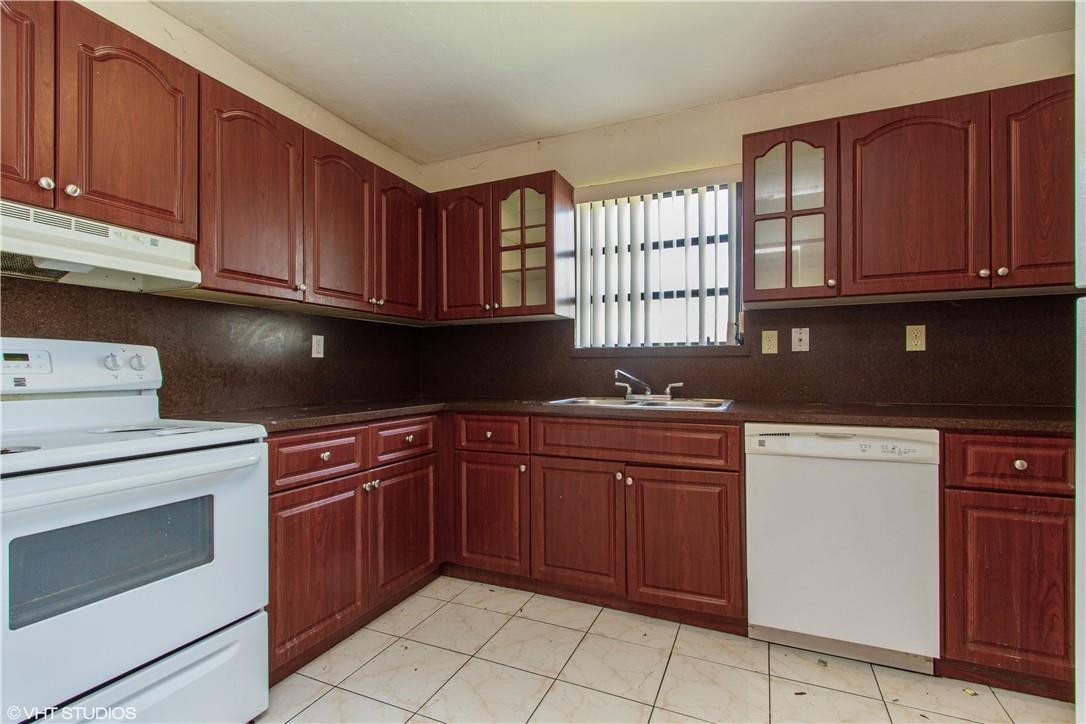 11398 Southwest 227th Terrace Miami, FL 33170 - Photo 7 of 13 a kitchen with granite countertop wooden cabinets stainless steel appliances and a window
