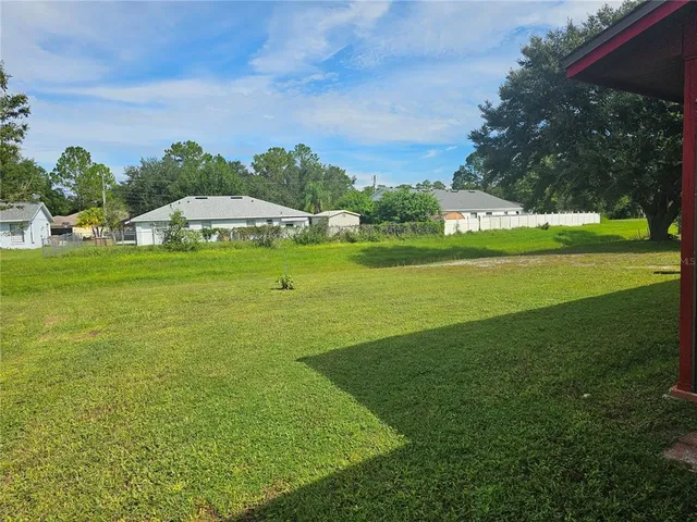 a view of a big yard with a table and chair under an umbrella