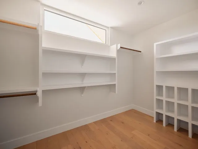 a view of an empty room with wooden floor and closet