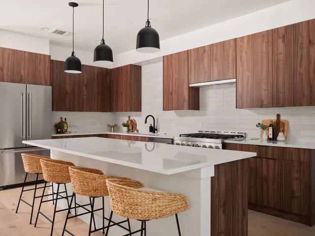 a kitchen with stainless steel appliances granite countertop a sink a stove a refrigerator and island with wooden cabinets