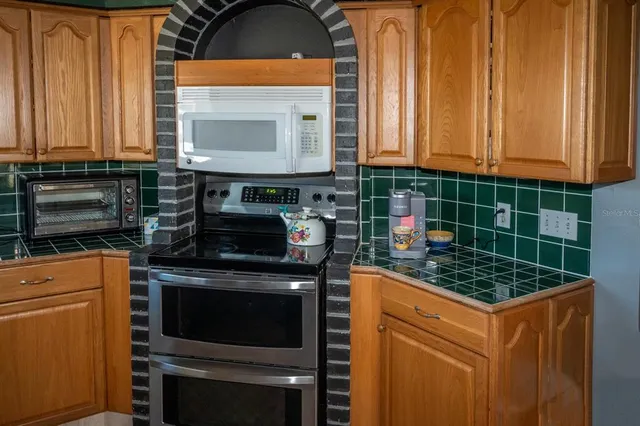 a kitchen with stainless steel appliances granite countertop a stove a sink and a microwave