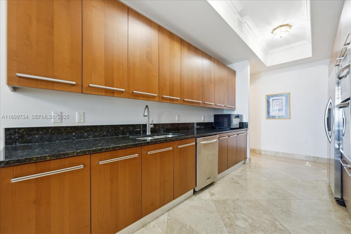 704 North Ocean Boulevard, Unit 1002 Pompano Beach, FL 33062 - Photo 22 of 57 a kitchen with stainless steel appliances granite countertop wooden cabinets a sink and dishwasher