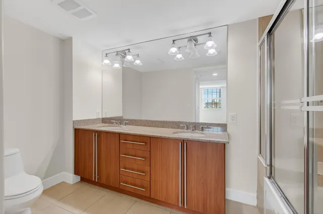 a bathroom with a granite countertop sink toilet a mirror and shower