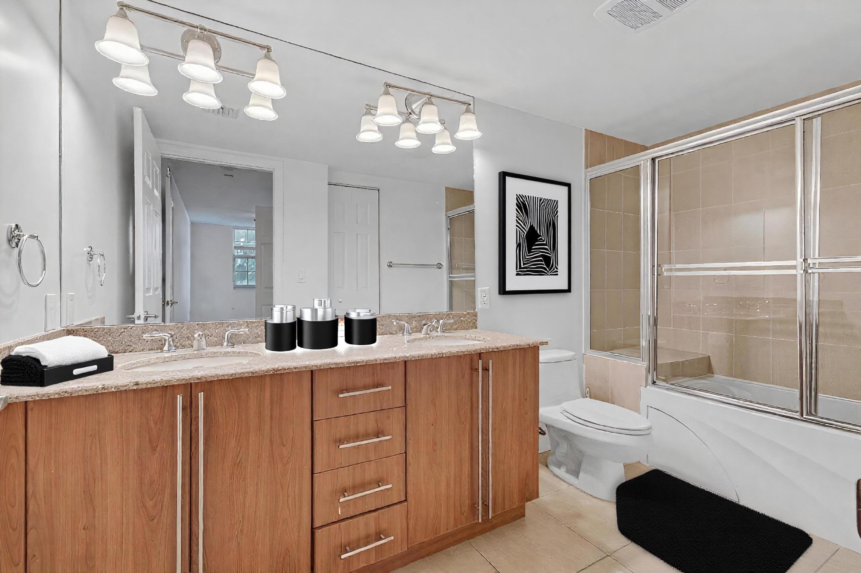 610 Clematis Street, Unit 532 West Palm Beach, FL 33401 - Photo 49 of 63 a bathroom with a granite countertop sink toilet a mirror a vanity and shower