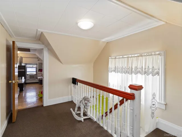 a view of a hallway with a livingroom with wooden floor and windows
