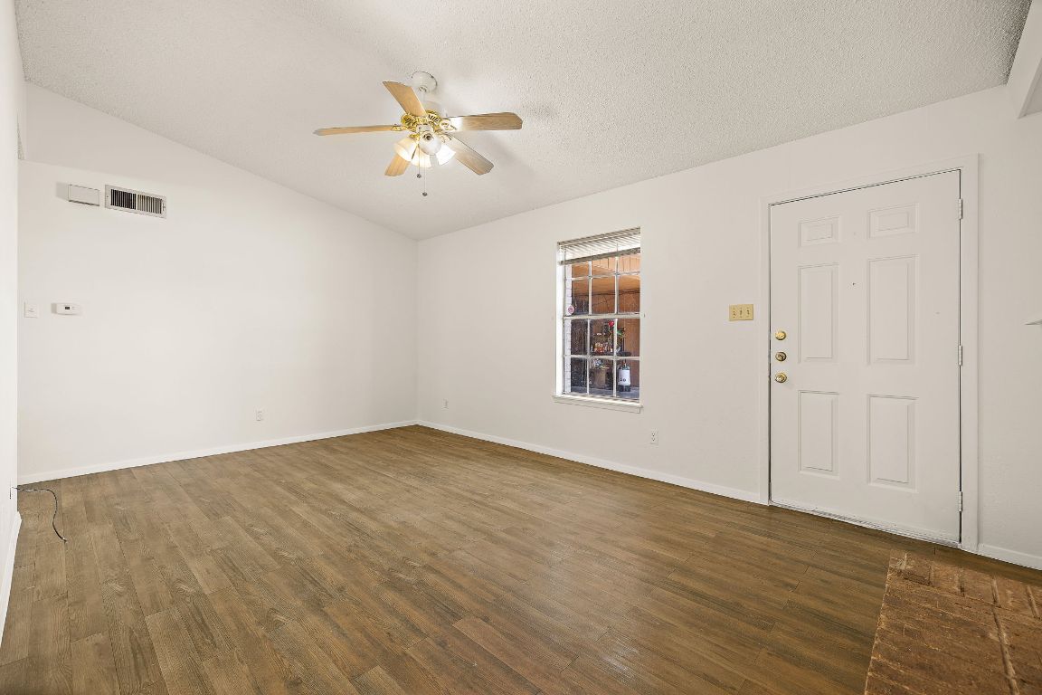 2402 Cottonwood Drive, Unit B Georgetown, TX 78628 - Photo 5 of 20 an empty room with wooden floor chandelier fan and windows