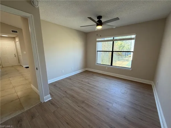 an empty room with wooden floor fan and windows