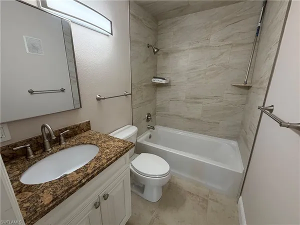a bathroom with a granite countertop sink toilet mirror and shower