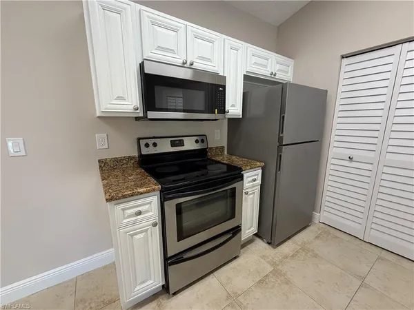 a kitchen with granite countertop white cabinets and stainless steel appliances