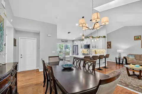 a dining room with wooden floor a chandelier a wooden table and chairs