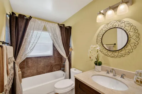 a bathroom with a granite countertop sink toilet and a mirror