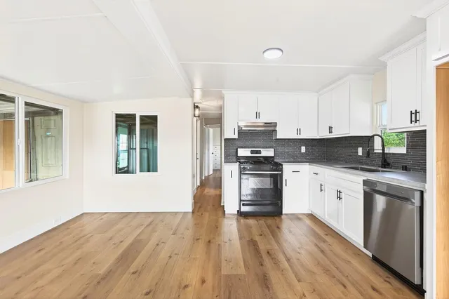 a kitchen with granite countertop a refrigerator stove top oven and sink with wooden floor