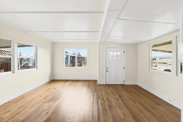 a view of an empty room with wooden floor and a window