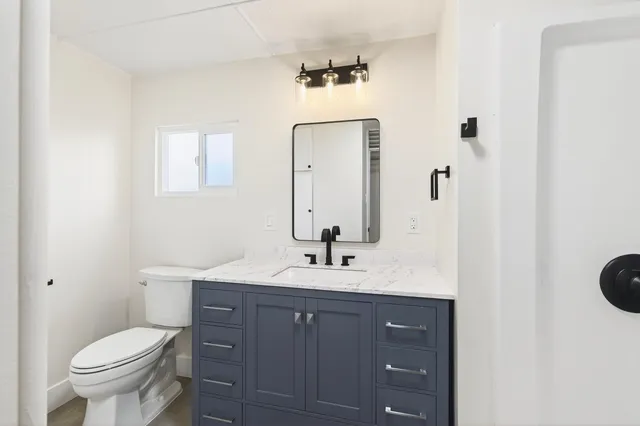 a bathroom with a toilet a sink a vanity and mirror
