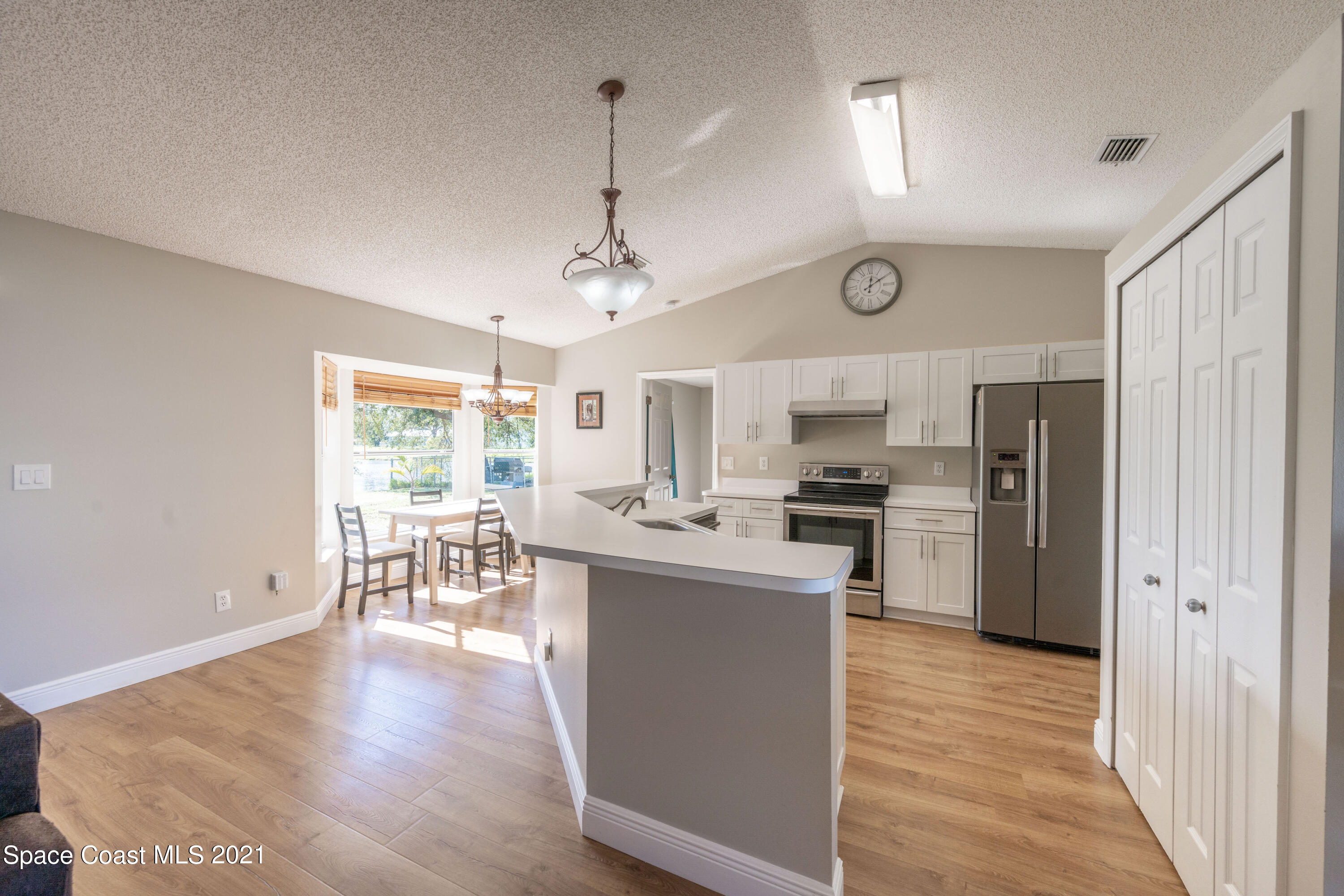 265 Oak Lake Road Melbourne, FL 32901 - Photo 6 of 25 a kitchen with stainless steel appliances granite countertop a refrigerator a stove top oven a sink dishwasher and white cabinets with wooden floor