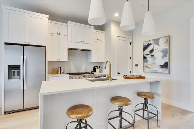 a kitchen with stainless steel appliances a sink a stove a refrigerator and cabinets