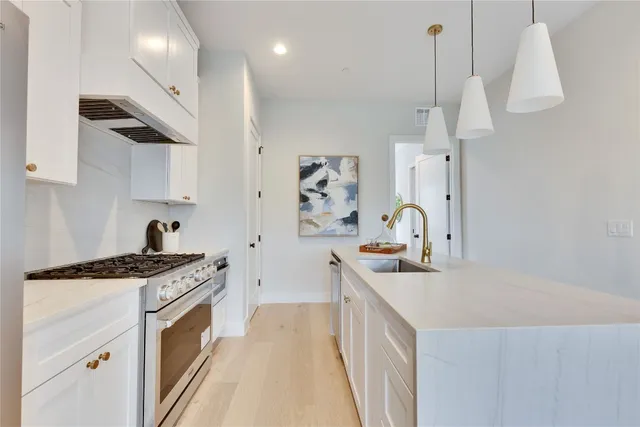 a kitchen with stainless steel appliances granite countertop a sink a stove and a wooden floors