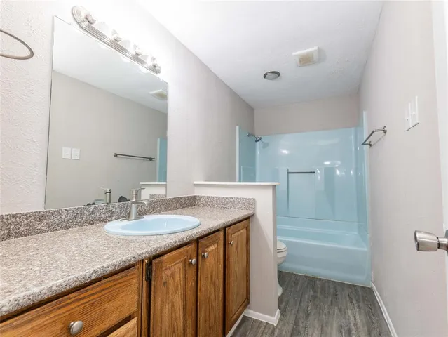 a bathroom with a granite countertop sink a toilet a large mirror and shower