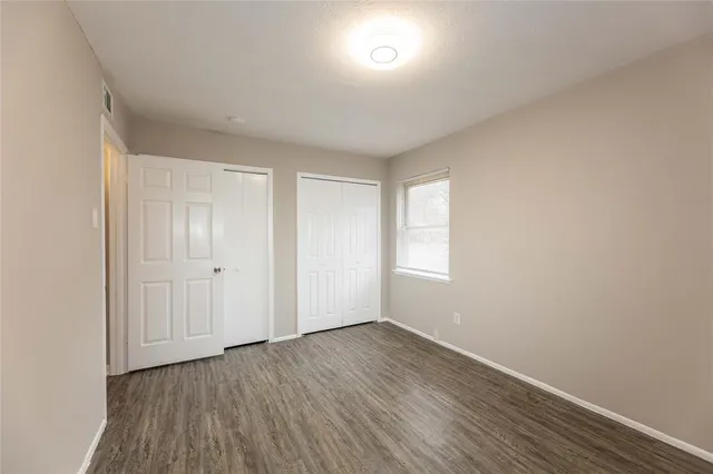 a view of an empty room with wooden floor and closet