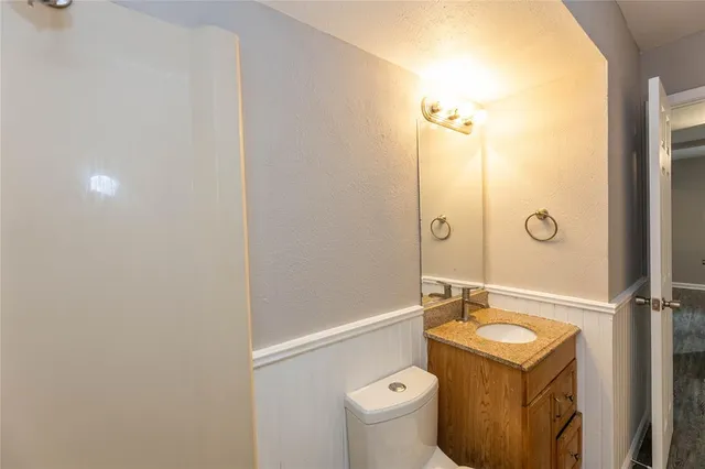 a bathroom with a granite countertop sink toilet mirror and shower
