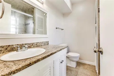 a bathroom with a granite countertop sink a toilet and a mirror